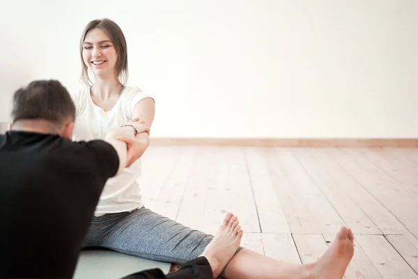 Laki-laki dan perempuan duduk di lantai kayu berlatih peregangan — Stok Foto