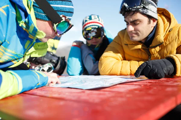 Três jovens snowboarders explorando o mapa no resort de inverno  . — Fotografia de Stock