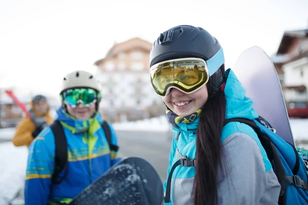 Image de femme heureuse en masque avec snowboard à la main et les hommes à la station de neige  . — Photo
