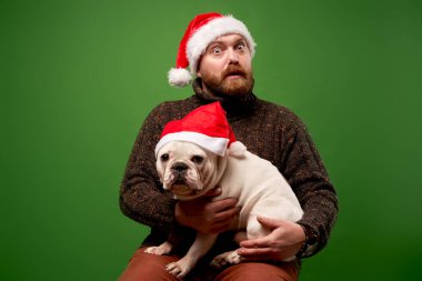 Noel Baba şapkalı sakallı erkek ve köpek boş yeşil arka planda.