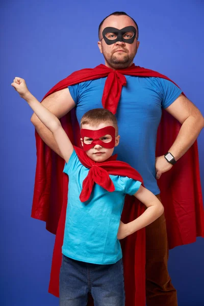 Papa et fils super héros en manteaux rouges sur fond bleu vierge — Photo
