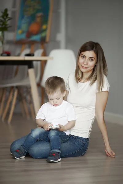 Mulher e pequeno filho sentado no chão no apartamento — Fotografia de Stock