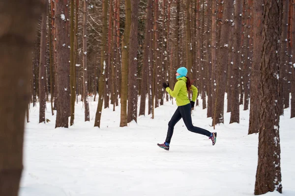 冬の森を走る若いスポーツウーマンの写真 — ストック写真