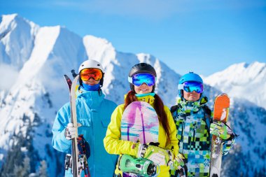 Mutlu sporcu kadın ve kayak ve snowboard yapan erkeklerin fotoğrafı kayak merkezinde duruyor.