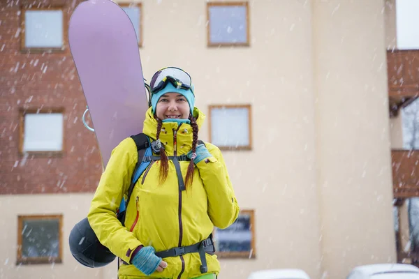 Imagen de deportista con tabla de snowboard sobre fondo de edificio en complejo de nieve . —  Fotos de Stock