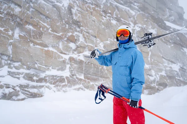 Bild des Sportlers mit Helm und Skiern in der Hand auf dem Hintergrund des Berges — Stockfoto