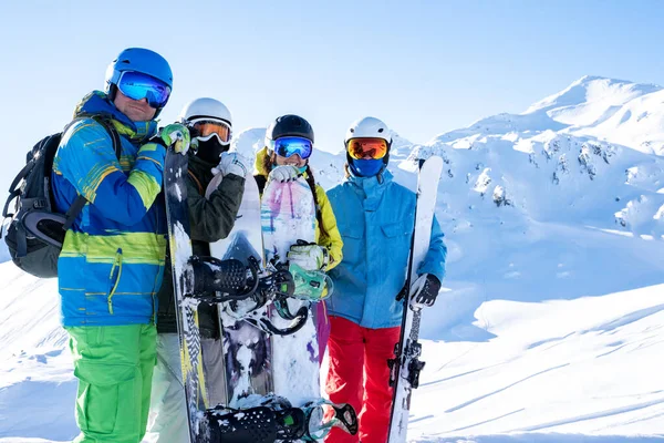 Photo de quatre athlètes portant un casque et tenant des planches à neige à la station de ski  . — Photo
