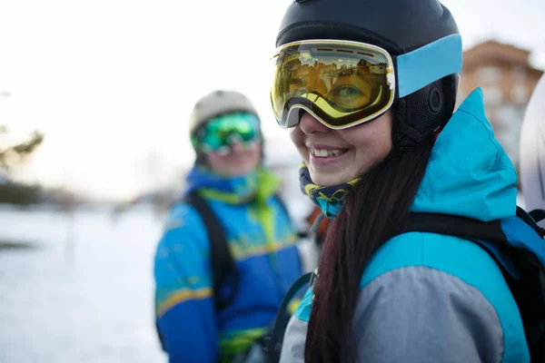 Photo d'une femme souriante masquée au snowboard et d'hommes à la station de ski . — Photo