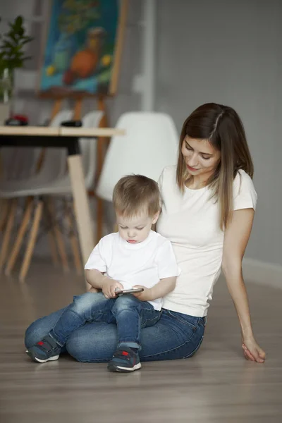 Junge Frau und kleiner Sohn sitzen in Wohnung auf dem Boden — Stockfoto