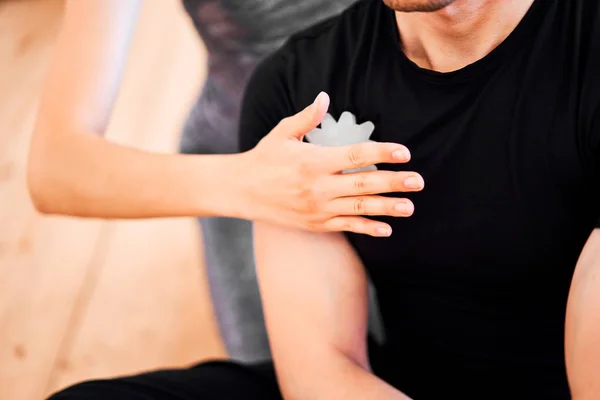 Женщина делает массаж мужчине в черной футболке с массажным мячом — стоковое фото
