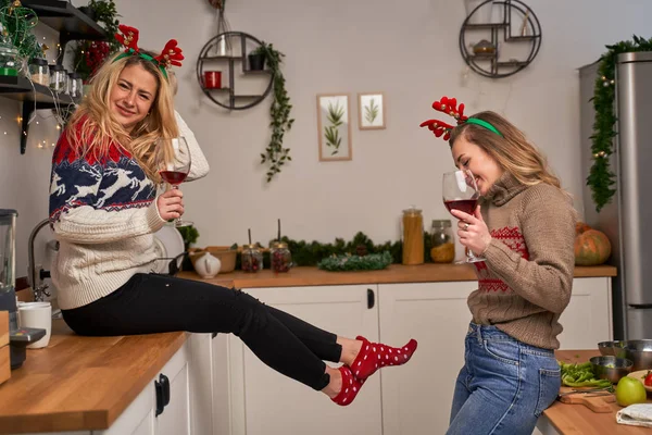 Zwei glückliche Frauen mit Weinglas stehen zu Weihnachten in der Küche. — Stockfoto