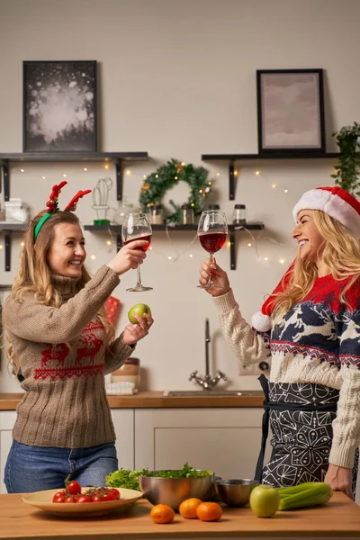 Δύο χαρούμενες γυναίκες με ποτήρια κρασιού για την Πρωτοχρονιά στην κουζίνα — Φωτογραφία Αρχείου