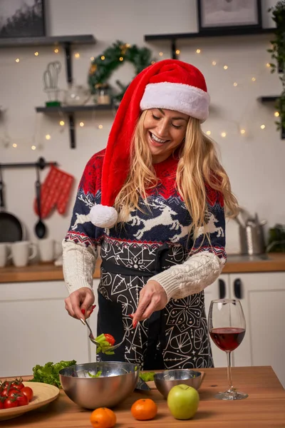 Noel Baba şapkalı mutlu kız mutfakta yemek pişiriyor..