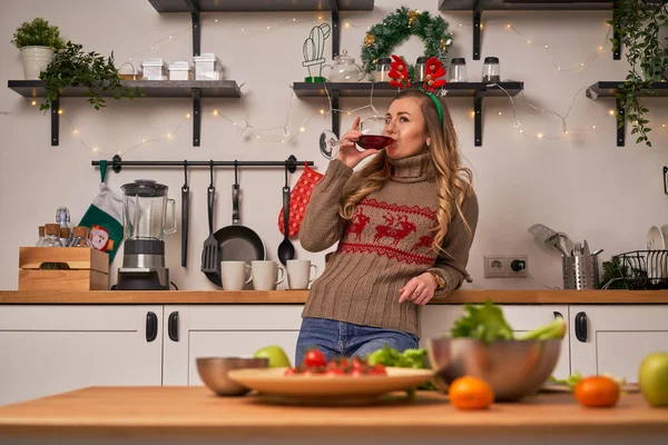 Junge Frau in weihnachtlichen Hirschhörnern trinkt Wein. Neujahrskonzept — Stockfoto