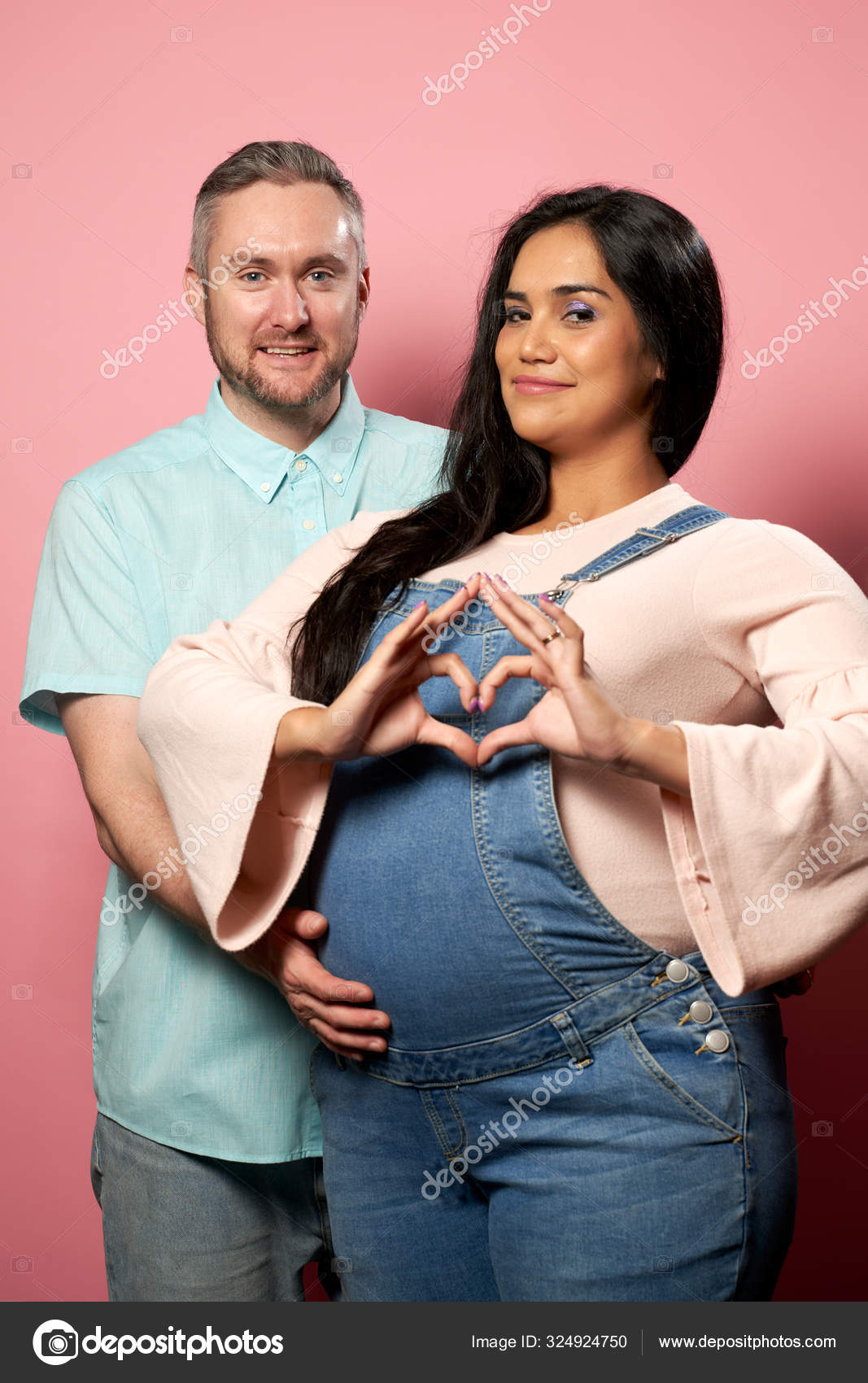 Hombre feliz y mujer embarazada en overol denim sobre fondo rosa vacio Foto de stock 324924750 logoff