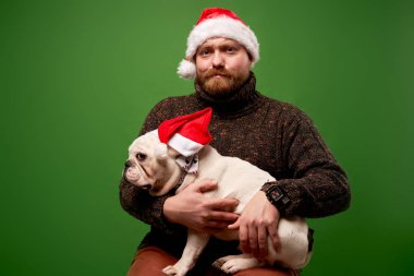 Noel Baba şapkalı adam ve köpek boş yeşil arka planda