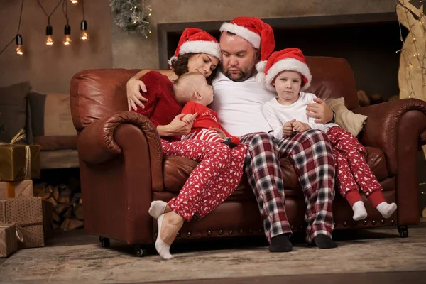 Imagem de pais felizes em bonés e filhos Santas no sofá de couro em estúdio — Fotografia de Stock