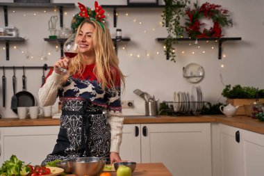 Noel 'de geyik boynuzları takan kız mutfakta şarap içiyor..