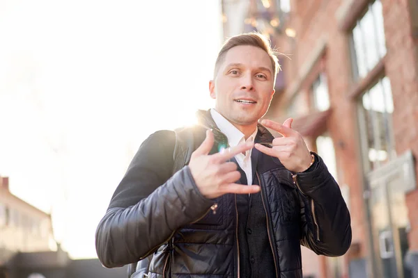 Brunet man on walk in city against backdrop of buildings at day. — Stock Photo, Image