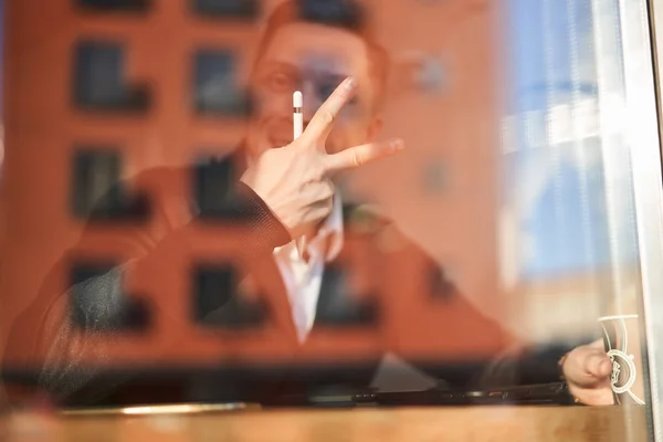 Uomo d'affari con telefono e tablet seduto nel caffè, edificio riflessione — Foto Stock