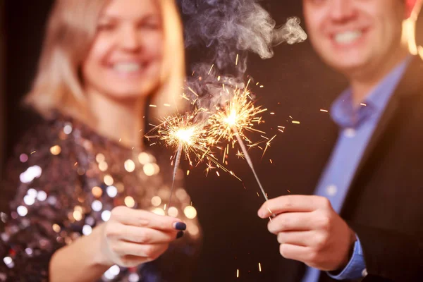 Image de couple heureux avec des verres à champagne et des étincelles sur fond noir — Photo