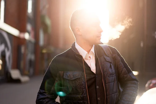 Hombre mirando a un lado caminando en la ciudad durante el día, efecto sol . — Foto de Stock