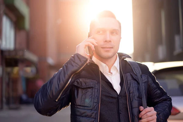 Mężczyzna rozmawiający przez telefon podczas spaceru po mieście w ciągu dnia, efekt światła słonecznego — Zdjęcie stockowe