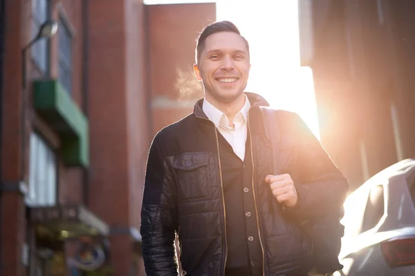 Jonge man op wandeling in de stad tegen de achtergrond van moderne gebouwen. — Stockfoto