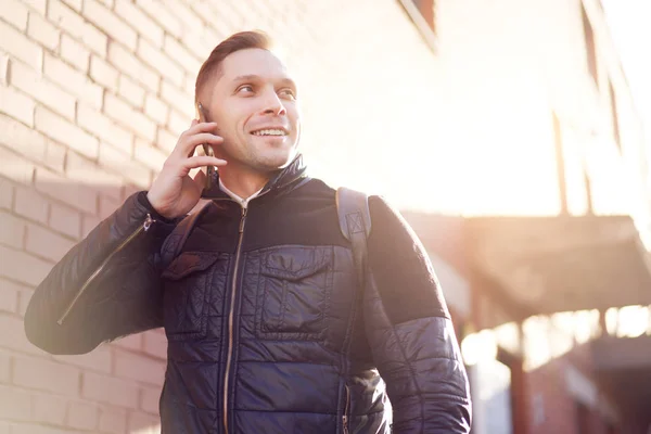 Mężczyzna rozmawiający przez telefon stojąc przy ceglanym nowoczesnym budynku na ulicy — Zdjęcie stockowe