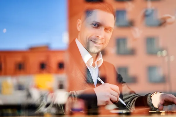 Homem feliz freelancer com telefone e tablet sentado no café, construção de reflexão — Fotografia de Stock