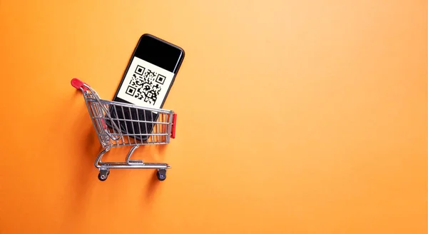 Carro pequeño de hierro con código para la lectura del supermercado sobre fondo naranja vacío —  Fotos de Stock