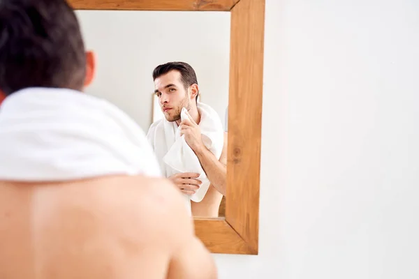 El hombre limpia su toalla mientras está de pie junto al espejo en el baño por la mañana . —  Fotos de Stock