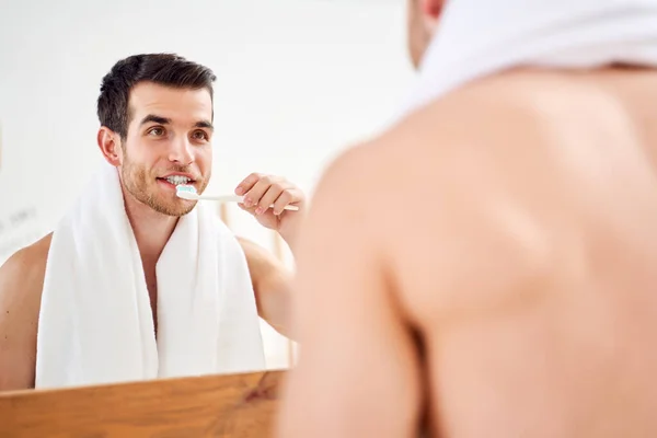 Young man brushes his teeth in front of mirror — 스톡 사진