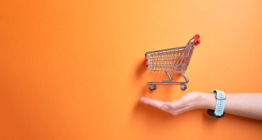 Süpermarketten demir küçük tramvay stüdyoda boş turuncu arka plan ve erkek palmiyesi.