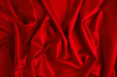 Kırmızı ipek kumaş dalgalar halinde yatıyor..