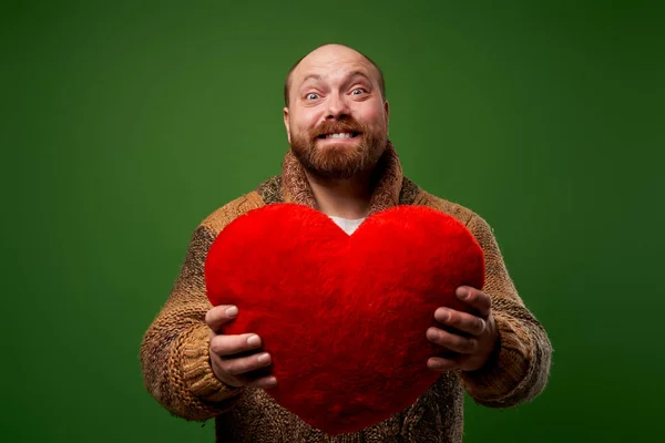 Ember tartja piros játék szív, miközben áll az üres zöld háttér — Stock Fotó