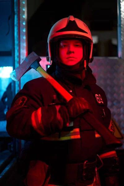 Close up firefighter male with hammer on his shoulder standing near fire engine — Stock Photo, Image