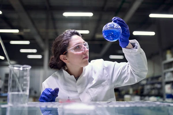 Young brunette laboratory assistant with petri dish in hands — Stok fotoğraf