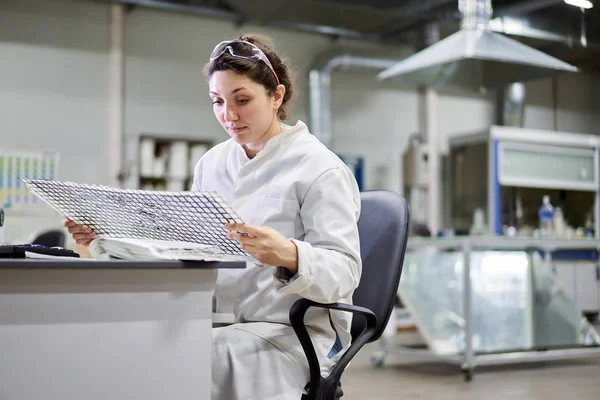 Young woman lab technician sitting at table with carbon mesh — Stok fotoğraf
