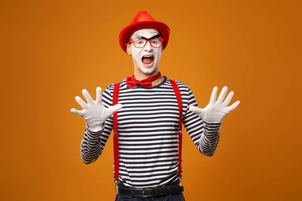 Verrast mime in rode hoed en gestreept t-shirt op blanco oranje achtergrond — Stockfoto