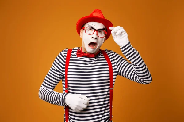 Jong verrast mime in rode hoed en gestreept t-shirt op blanco oranje achtergrond — Stockfoto