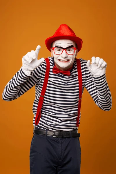 Smiling mime with white face in red hat and striped t-shirt on blank orange background — 스톡 사진