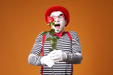 Kırmızı şapkalı, gözlüklü ve yelekli mutlu pandomimci.