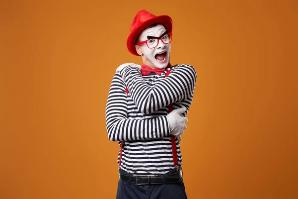 Boldog pantomim férfi mellényben és piros kalap narancson — Stock Fotó