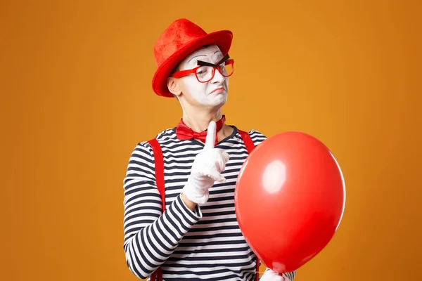 Клоун з червоним м'ячем на помаранчевому фоні — стокове фото