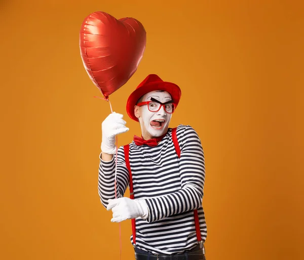 Happy mime em chapéu vermelho e colete mantém a bola do coração em suas mãos — Fotografia de Stock