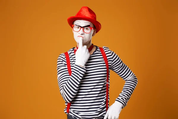 Verrast mime in rode hoed en vest op oranje achtergrond — Stockfoto