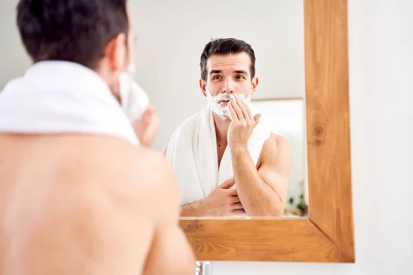 Brunet man with foam on beard near mirror in morning — Stock Photo, Image