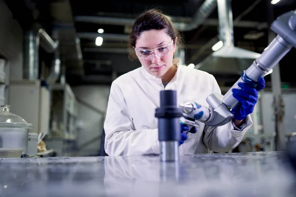 Female lab technician in blue rubber gloves with 3D printer on blurred background — Stock Photo, Image