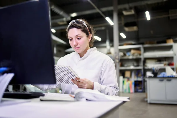 Женщина лаборант сидит за столом с компьютером и углеродной сеткой — стоковое фото